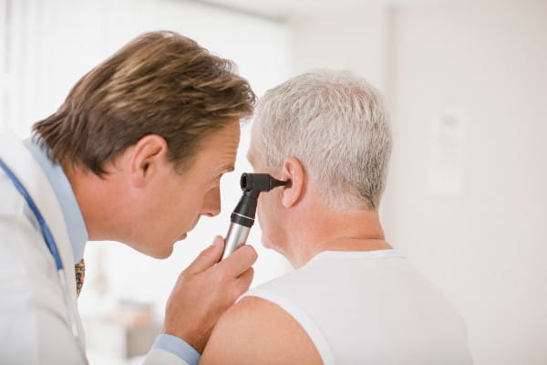 Doctor examining patients ear in doctors office