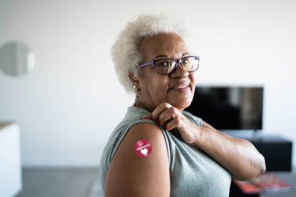 senior woman showing arm with 'Got vaccinated' sticker on
