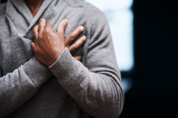 man holding his chest in pain indoors