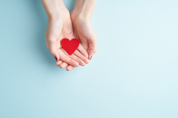 two hands holding small red heart