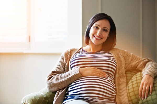 Portrait of a smiling pregnant woman sitting on her sofa