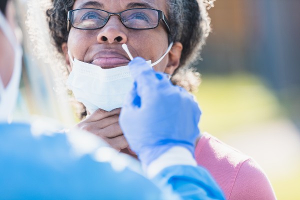 Mature woman grimaces in anticipation of nasal swab for COVID-19 