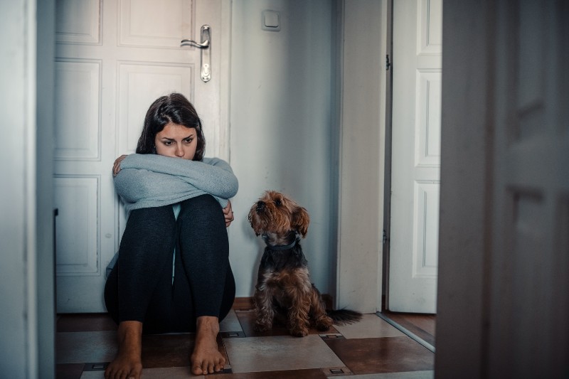 Woman with mental health problems is sitting desperate on the floor and crying