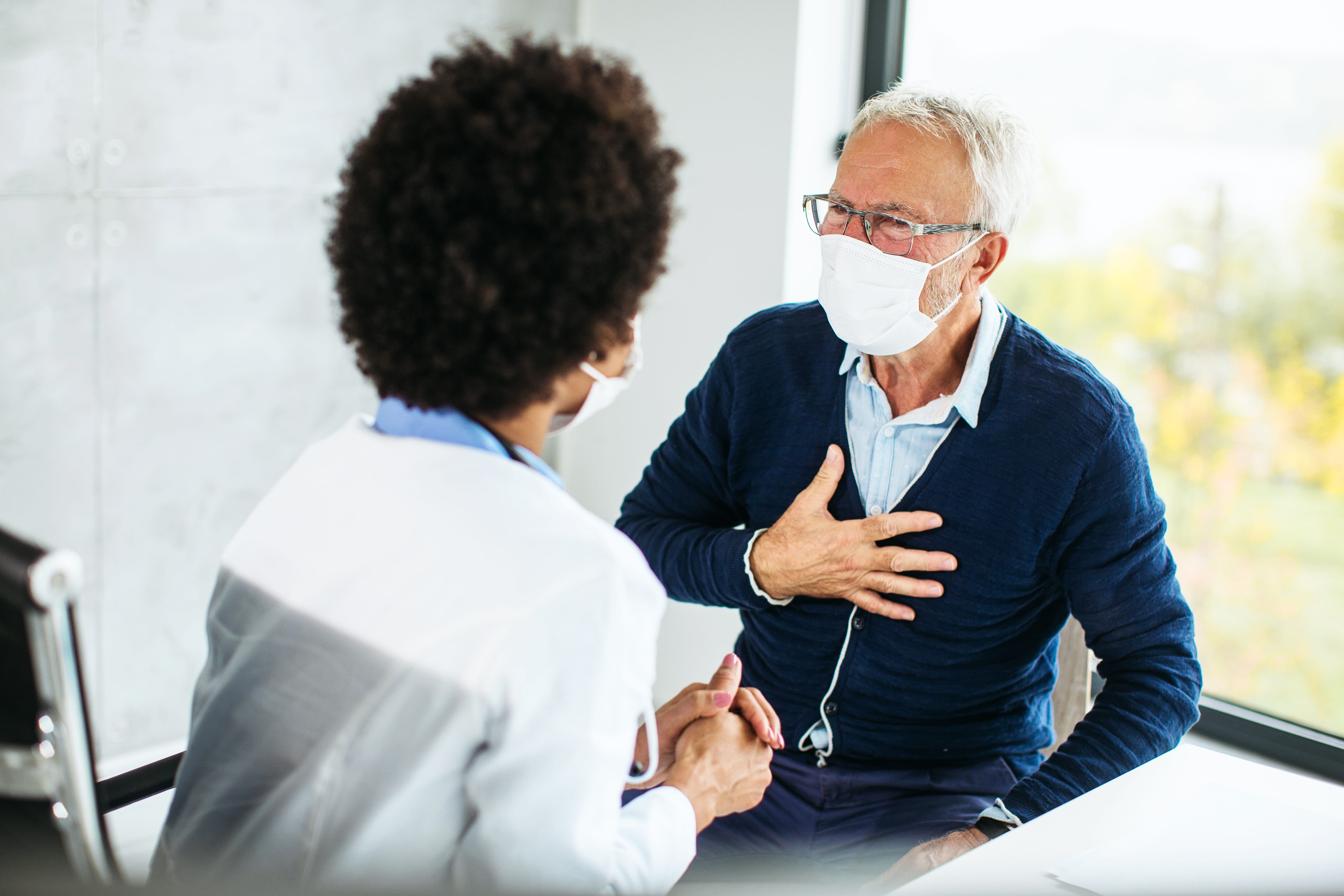 female doctor examining senior male patient in a modern office clinic 