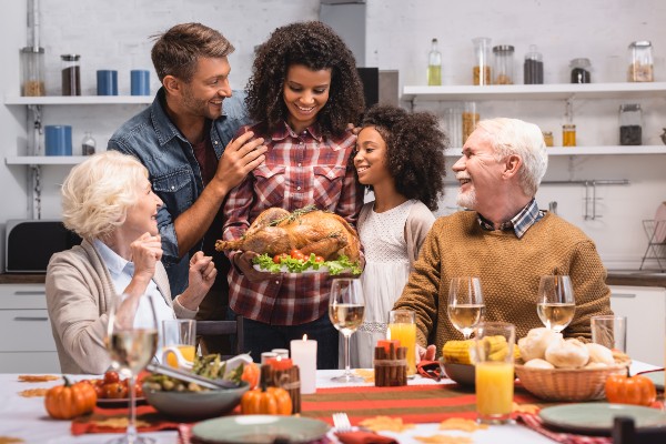 african american woman holding turkey near family during thanksgiving celebration