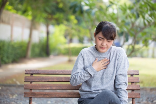 woman having heartburn at the park