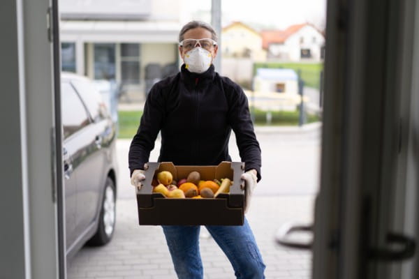 woman delivery person with box of fruits at door