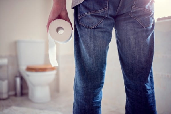 Man holding toilet paper roll in bathroom