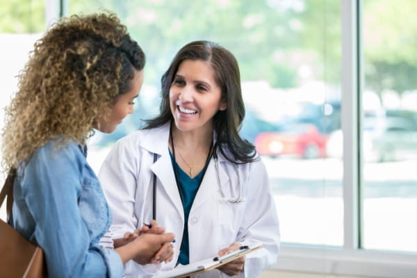 Female doctor discusses something with young mixed race patient