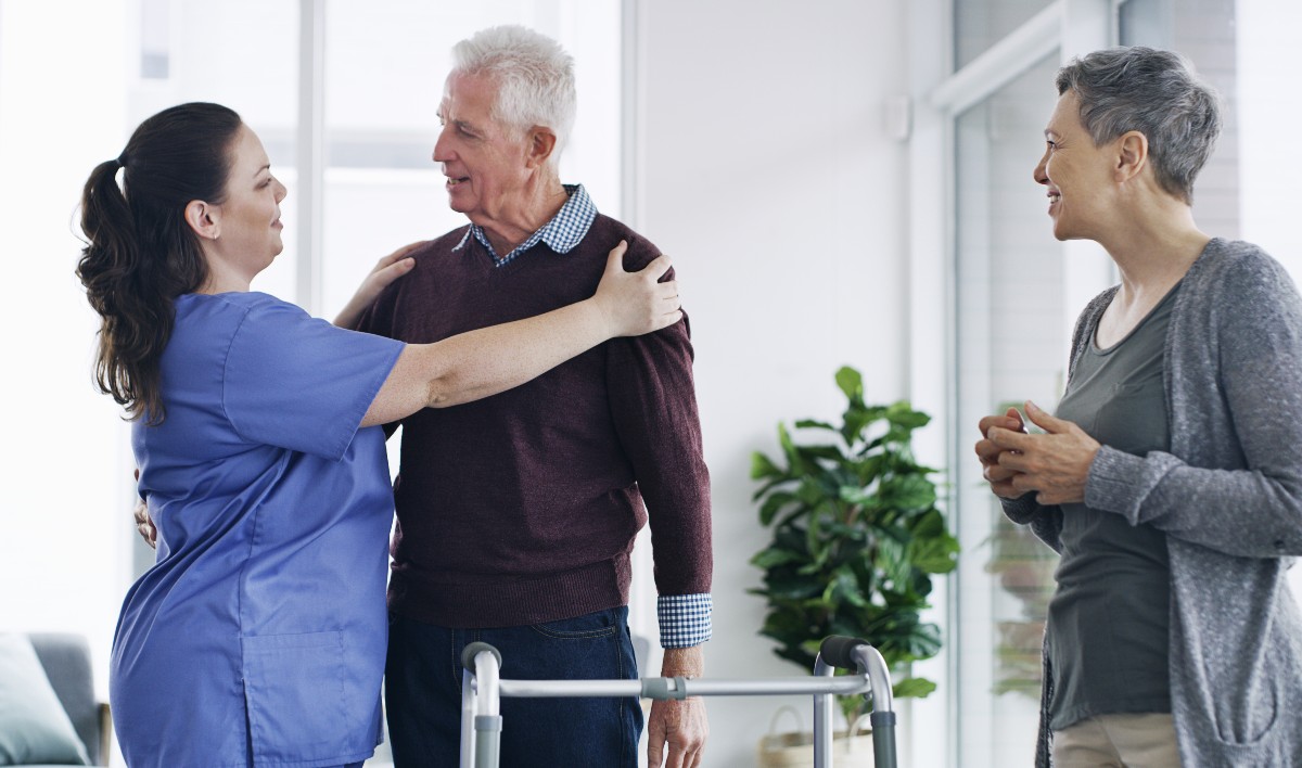 Shot of a senior man using a walker with his wife and nurse 