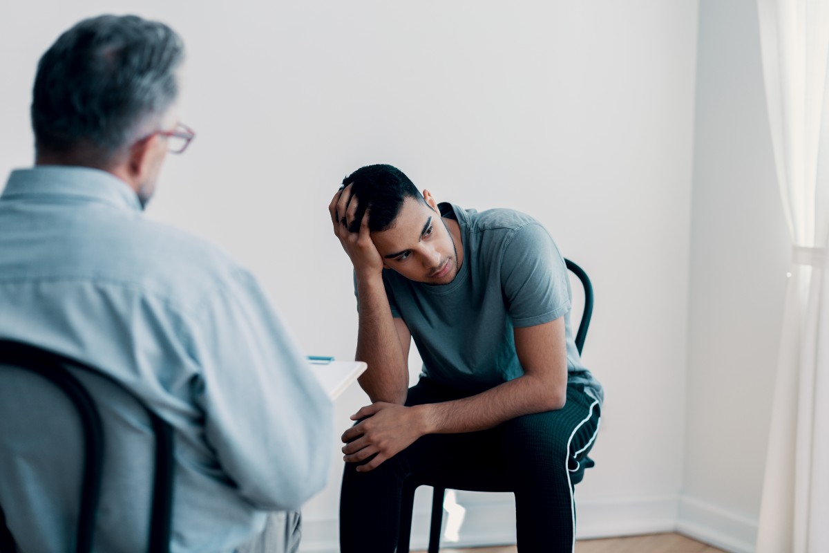 Depressed teenager looking away while talking to his therapist