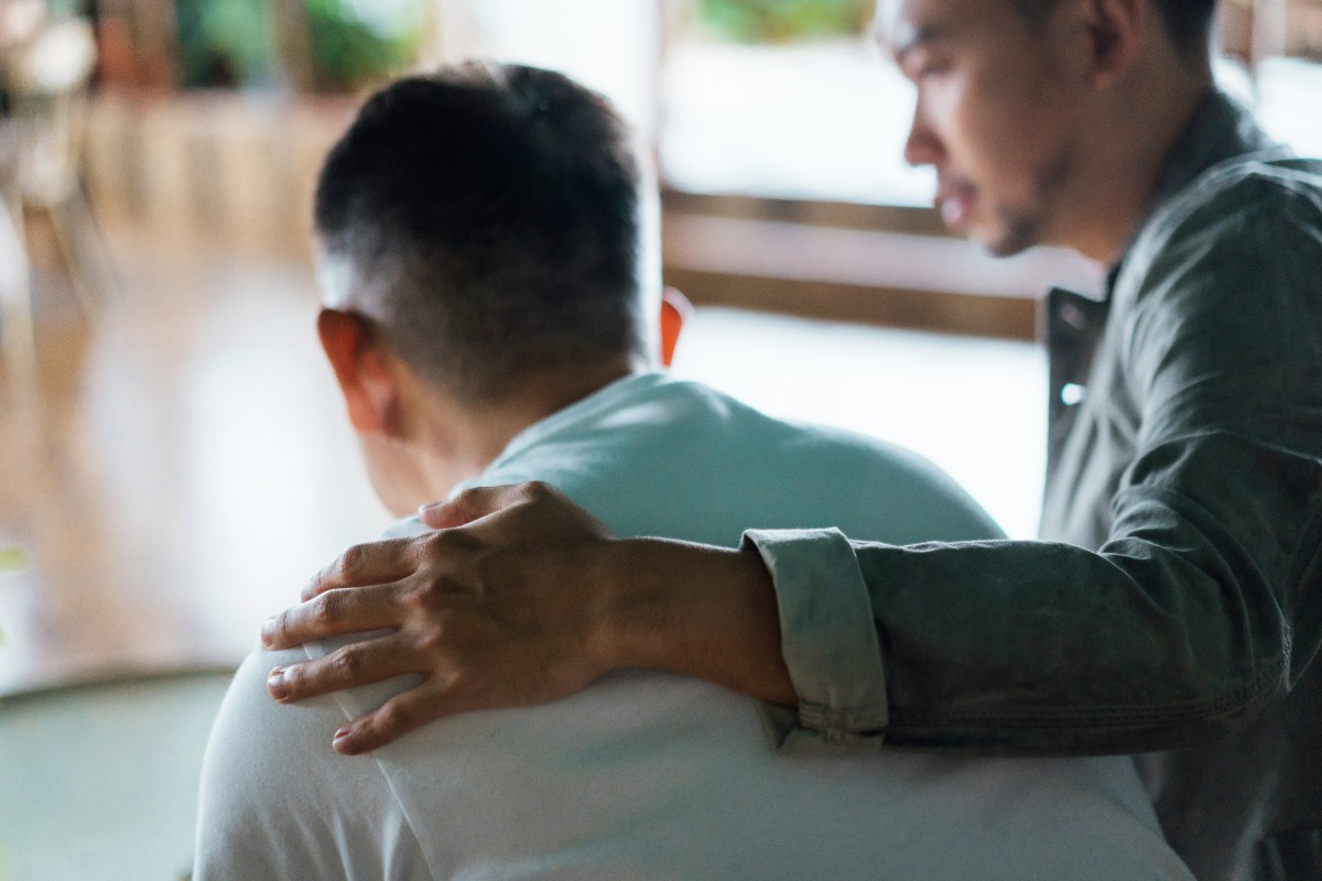 Rear view of son and elderly father sitting together at home