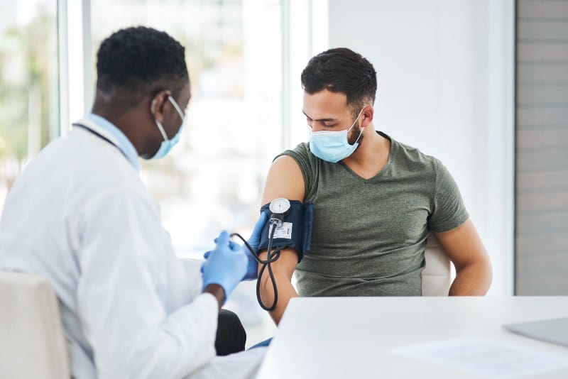 Shot of a doctor examining a young man with a blood pressure gauge