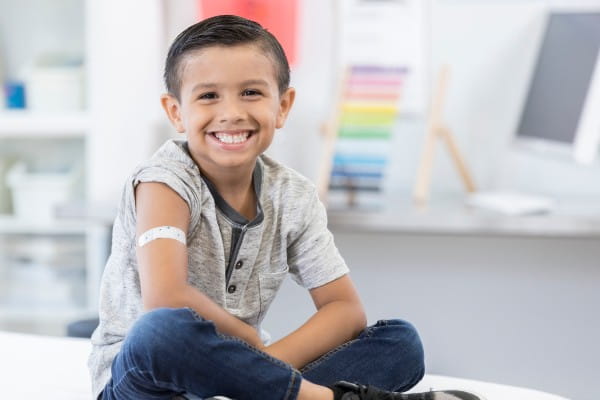 Kid smiling with band-aid on his arm