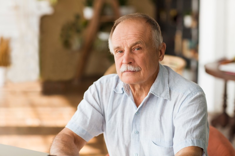  senior man thinking and looking at camera at home