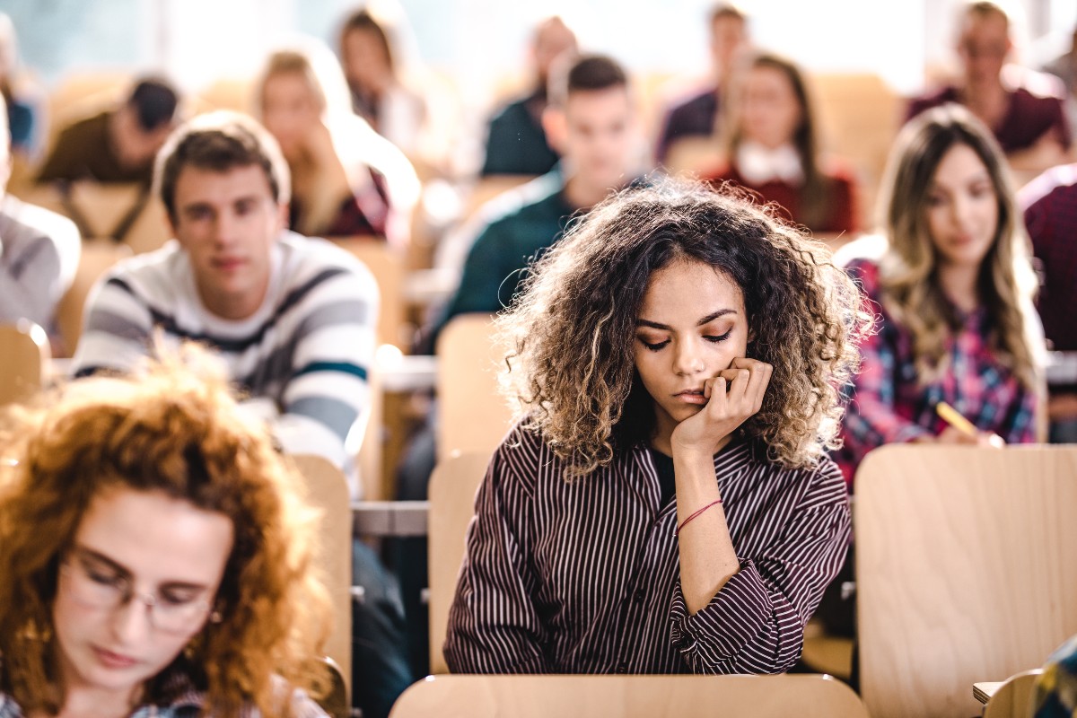 Female college student feeling bored on a class at lecture hall.