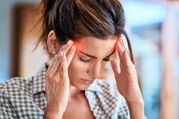 Shot of a uncomfortable looking woman holding her head in discomfort