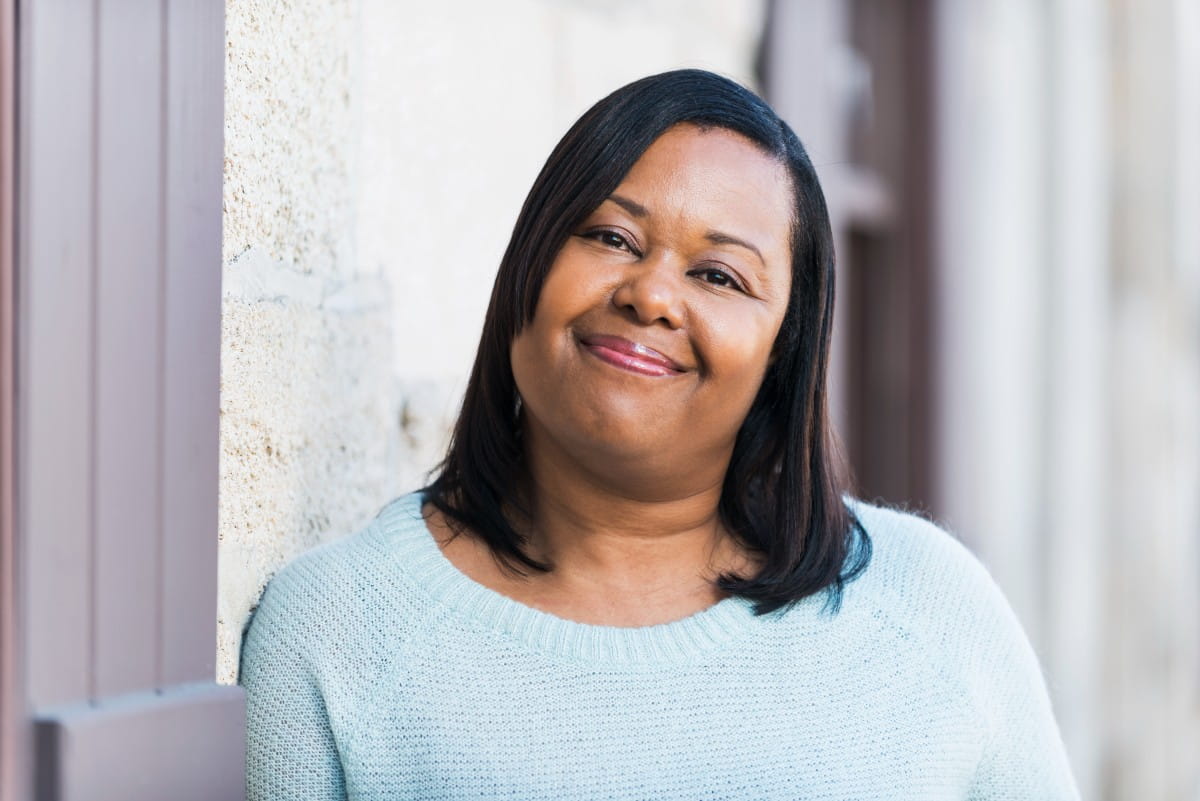 Portrait of a mature, African American woman standing outdoors, smiling at the camera