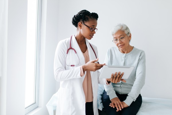 Black female doctor showing digital tablet to patient