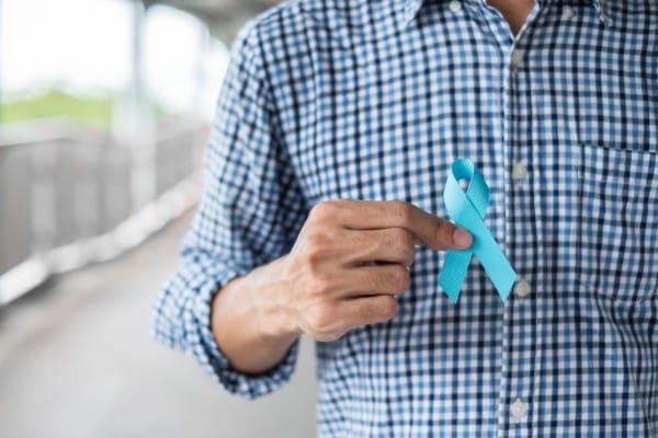 Man in blue shirt with hand holding Blue Ribbon