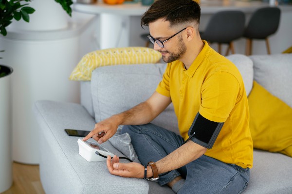 Man taking his blood pressure at home in the living room