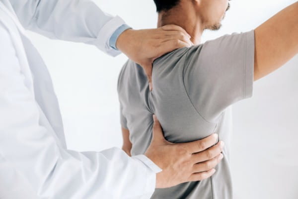 Sports Doctor doing healing treatment on man's shoulder