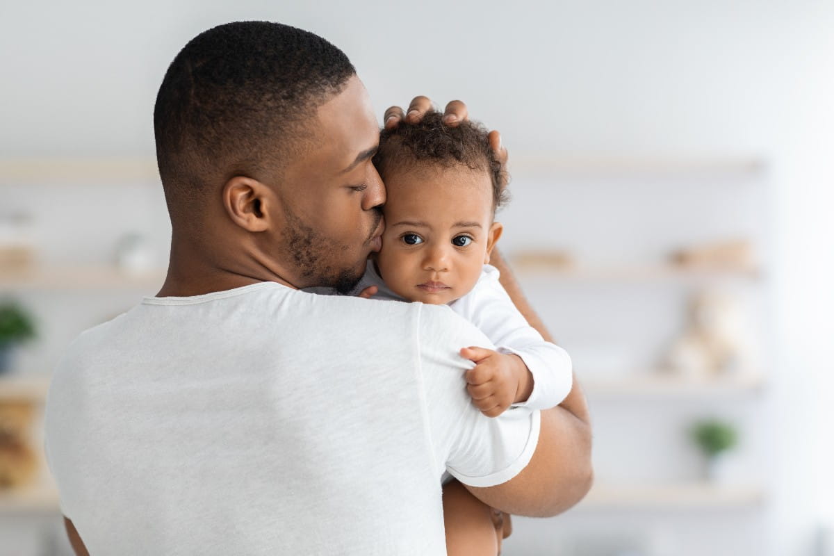  Young Black Dad Holding And Kissing Adorable Newborn Baby At Home