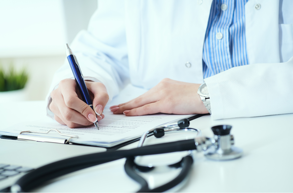 female doctor writes prescription to patient at worktable