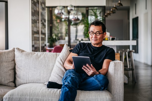 Man sitting on couch alone with tablet