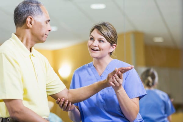 Female physical therapist helping male patient with injured arm