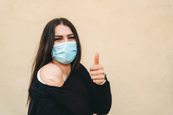 Caucasian woman smiling with a mask after receiving a shot