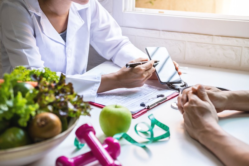 Nutritionist giving consultation to patient with healthy fruits and vegetables