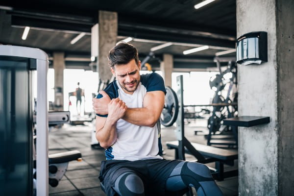 man grabbing his shoulder in the gym