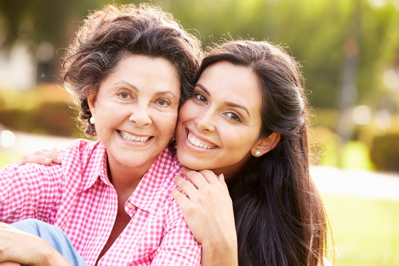 Mother With Adult Daughter In Park Together Smiling To Camera