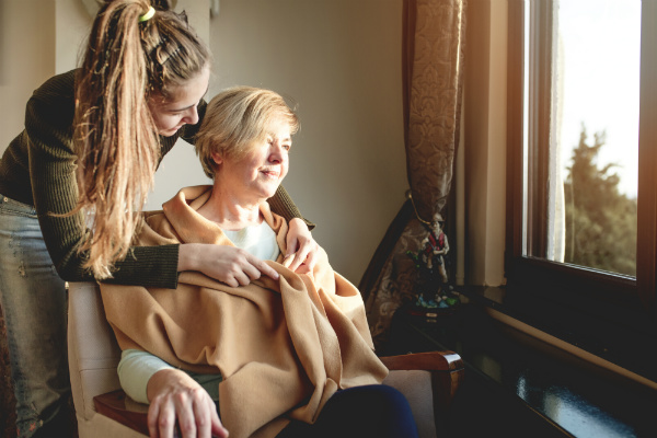 Young woman putting wrap around older woman