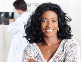 Woman smiling at camera with doctor in background