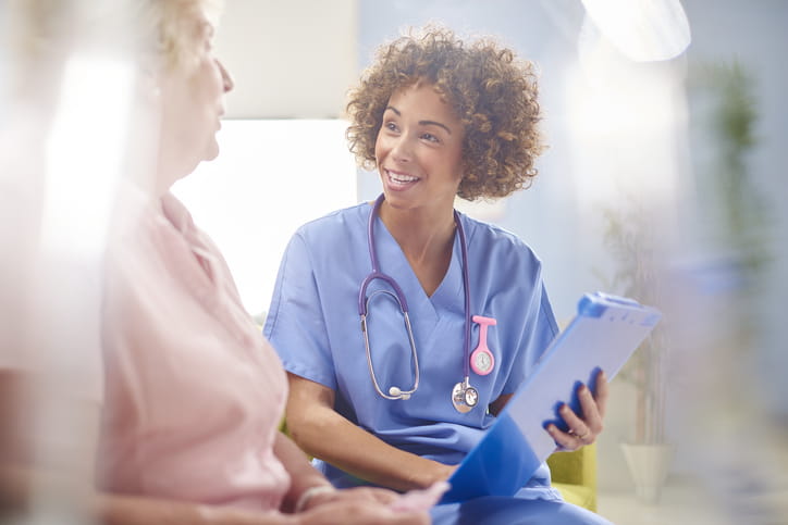 Nurse sitting with a woman patient going over paperwork