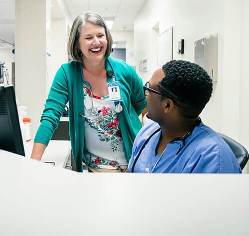 Doctor and nurse laughing near computer