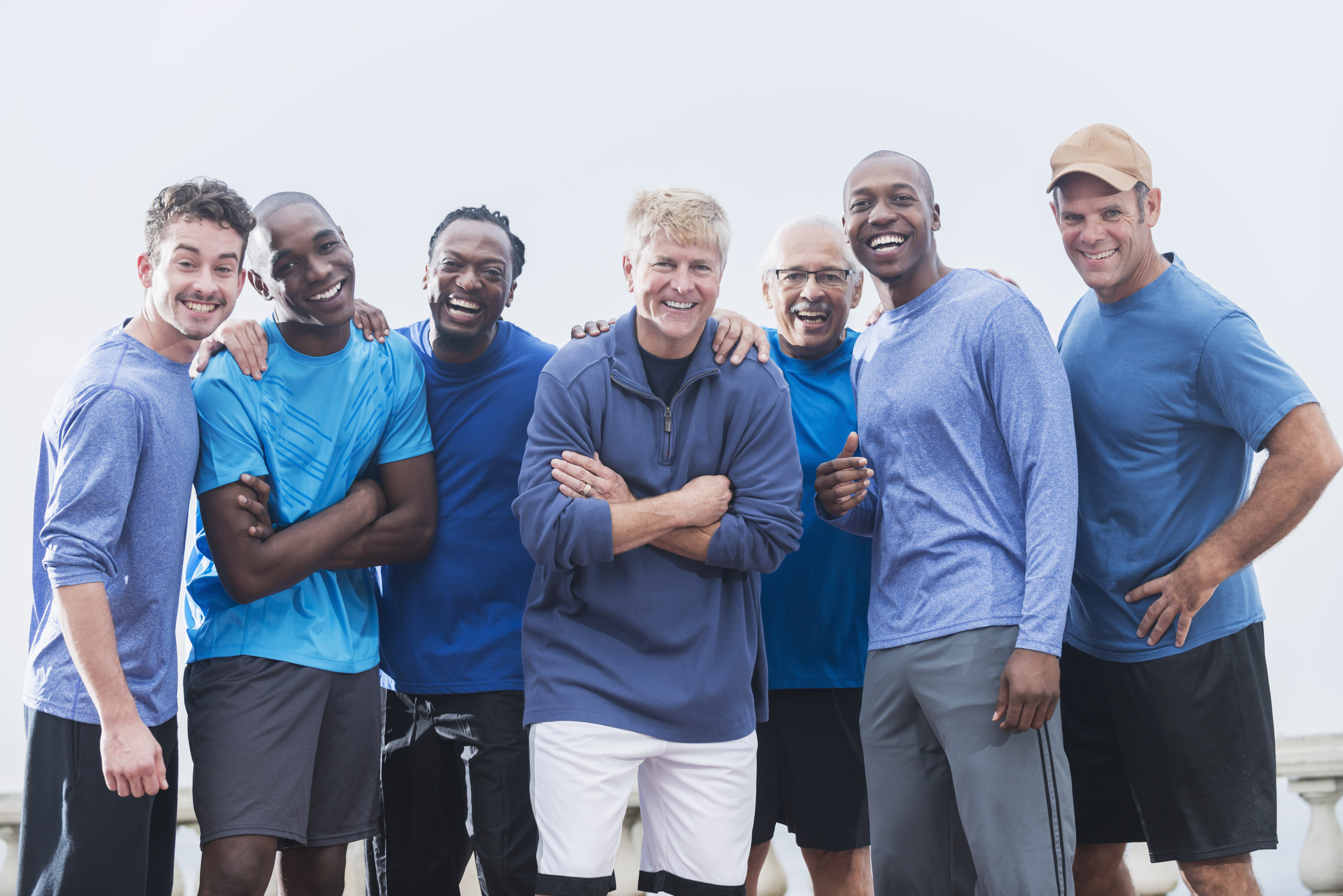 group of diverse men in blue shirts smiling in a group together